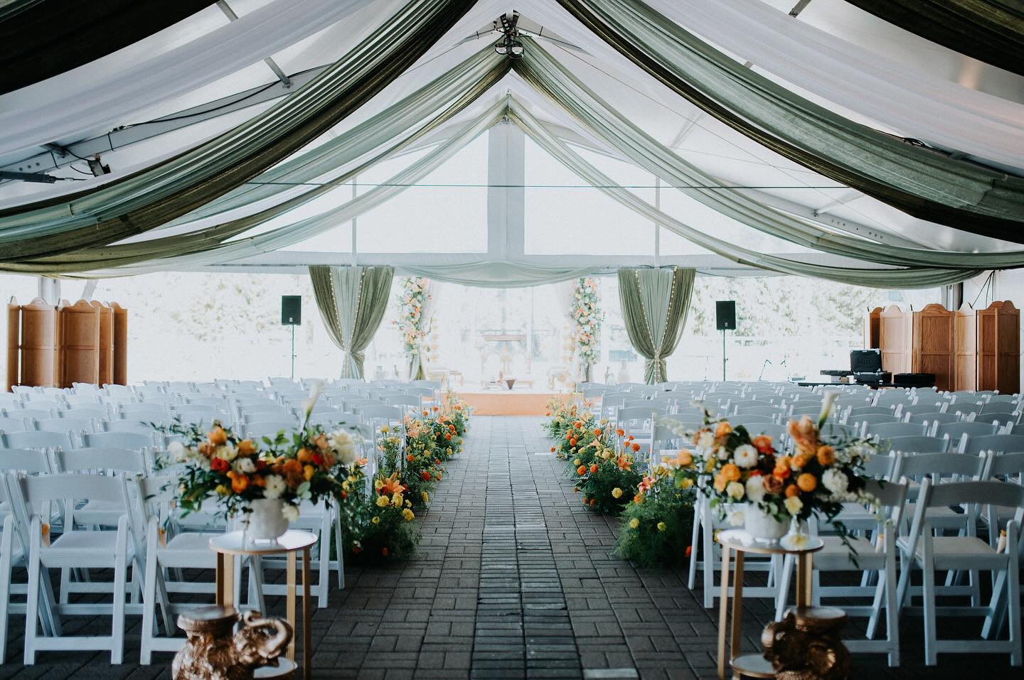 Draped tent ceremony with green silk ceiling and floral aisle by InStyle Events