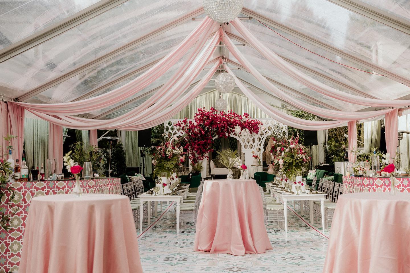 Elegant pink-draped tent reception with bougainvillea centrepiece and custom patterned flooring by InStyle Events