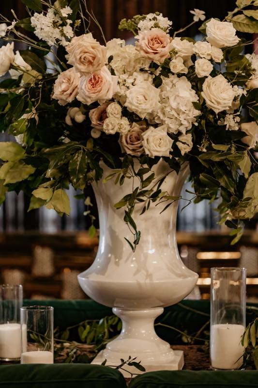 Bespoke floral arrangement — overflowing white urn with blush roses, peonies and greenery on velvet by InStyle Events