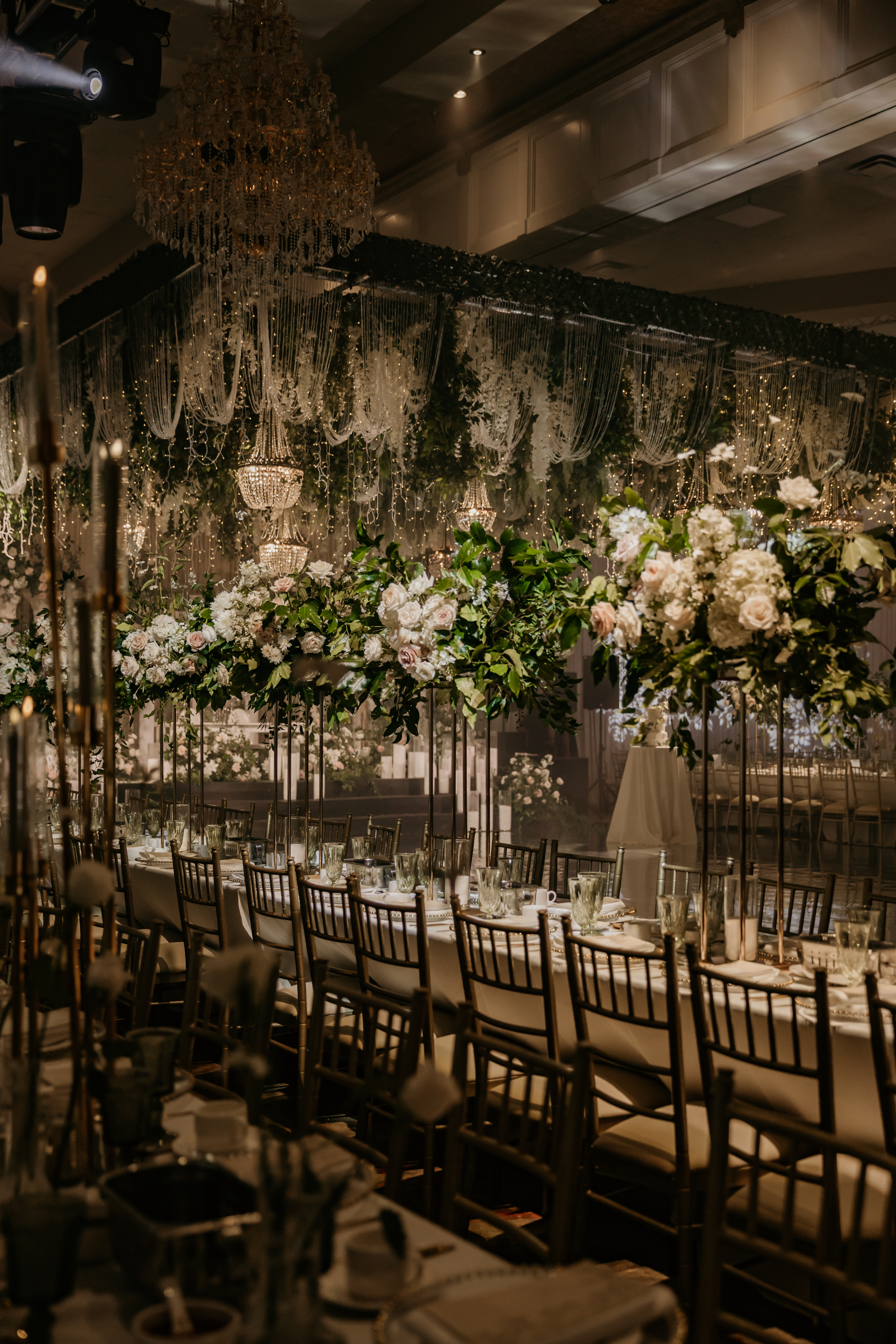 Long luxury dining table with towering fresh floral centrepieces on black gold stands and crystal glassware by InStyle Events
