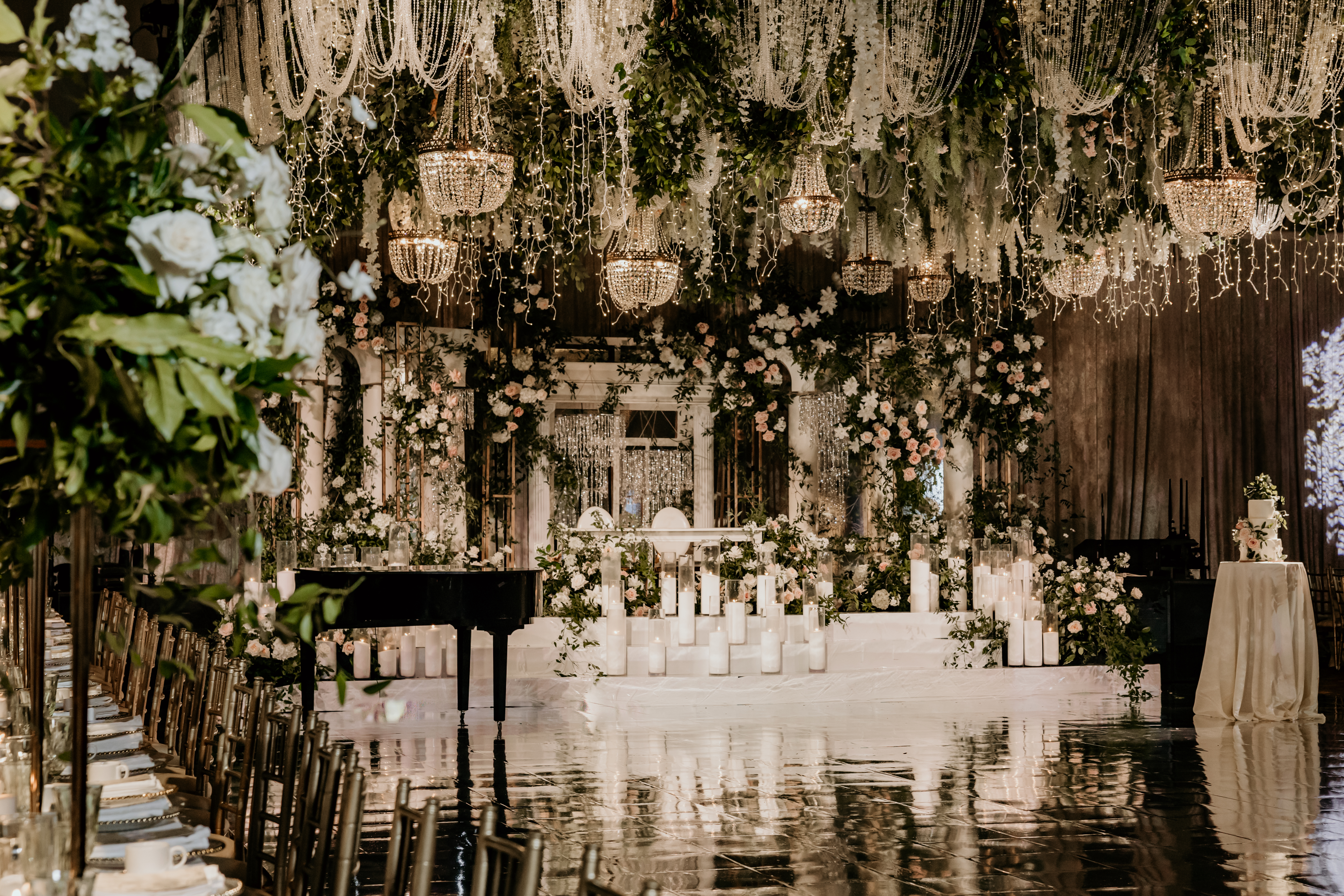 Grand wedding reception hall with crystal chandeliers, reflective floor and lush greenery ceiling by InStyle Events