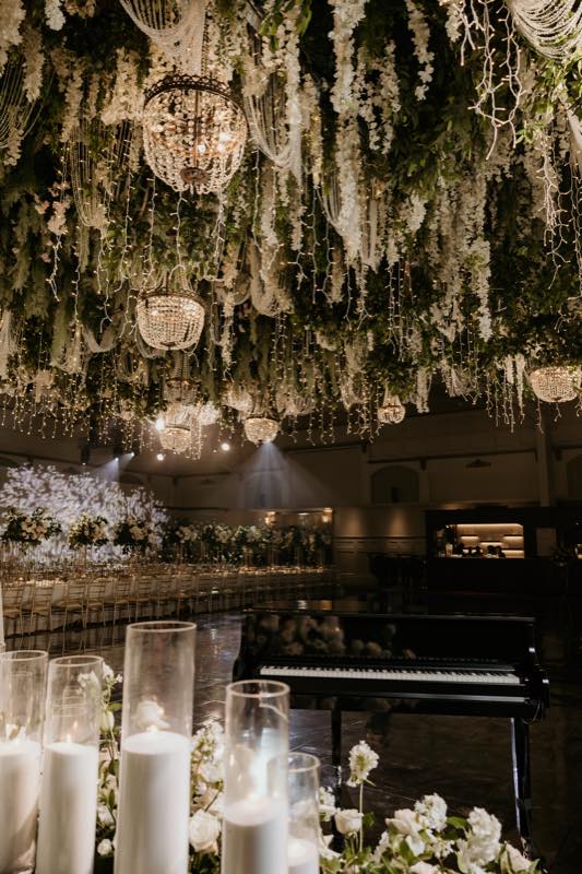 Crystal ball chandeliers with hanging wisteria, piano and pillar candles by InStyle Events